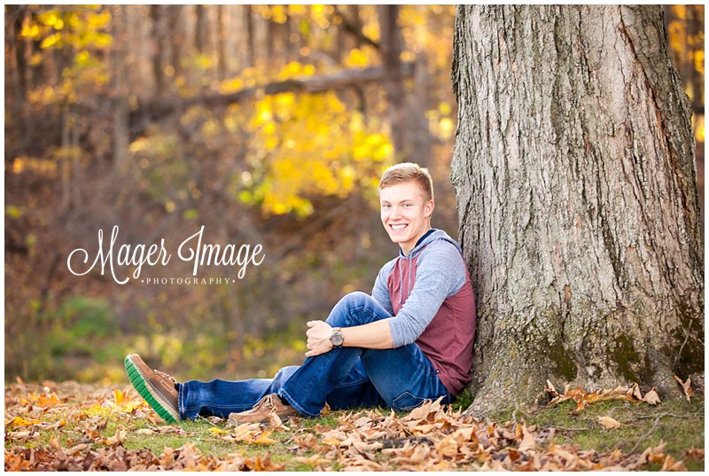fall boy sitting with tree