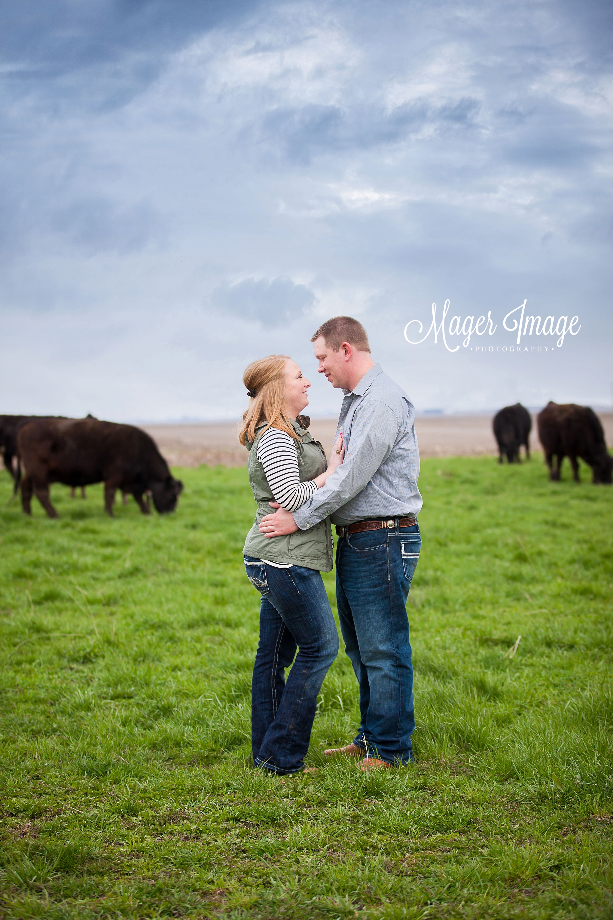 couple standing in a cow field blue sky