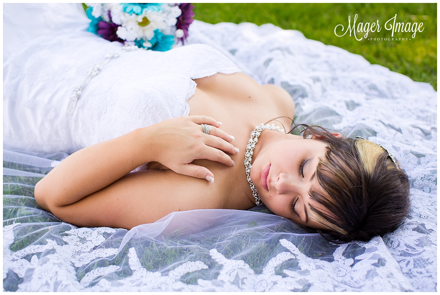 bride laying on veil in grass