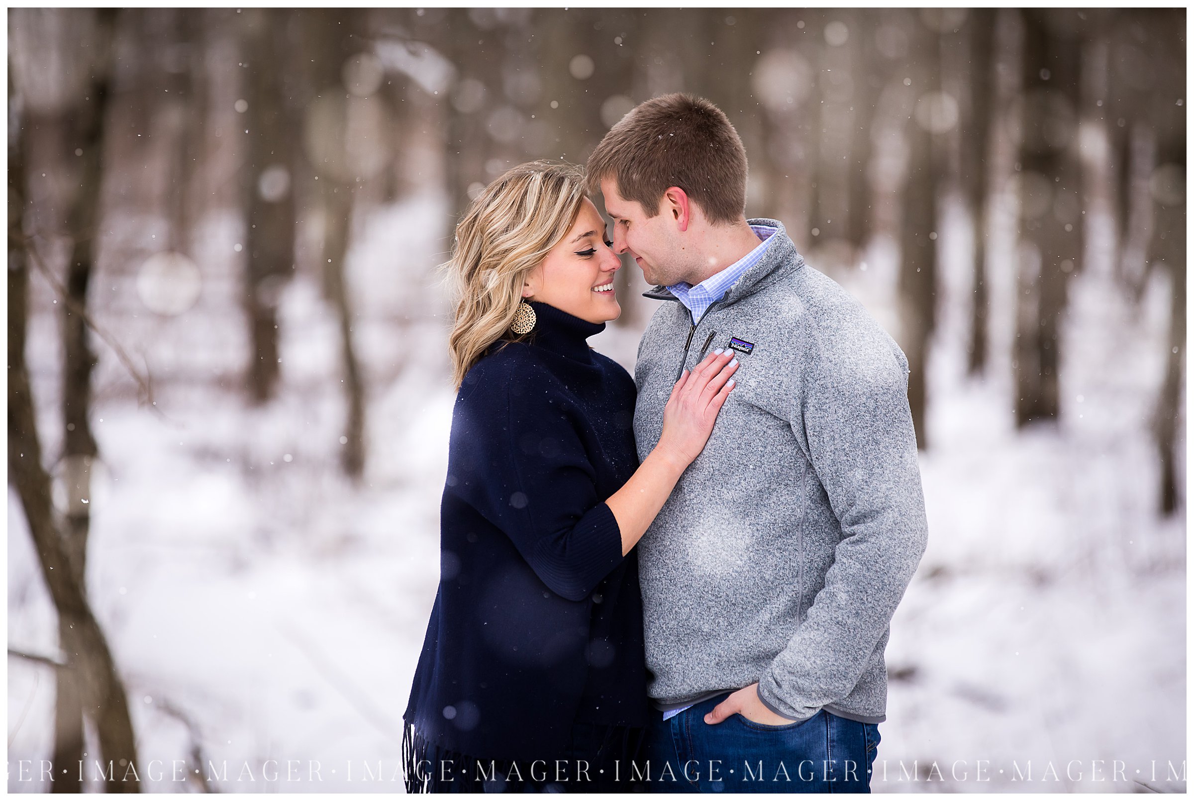 winter snow falling couple kissing engagement session