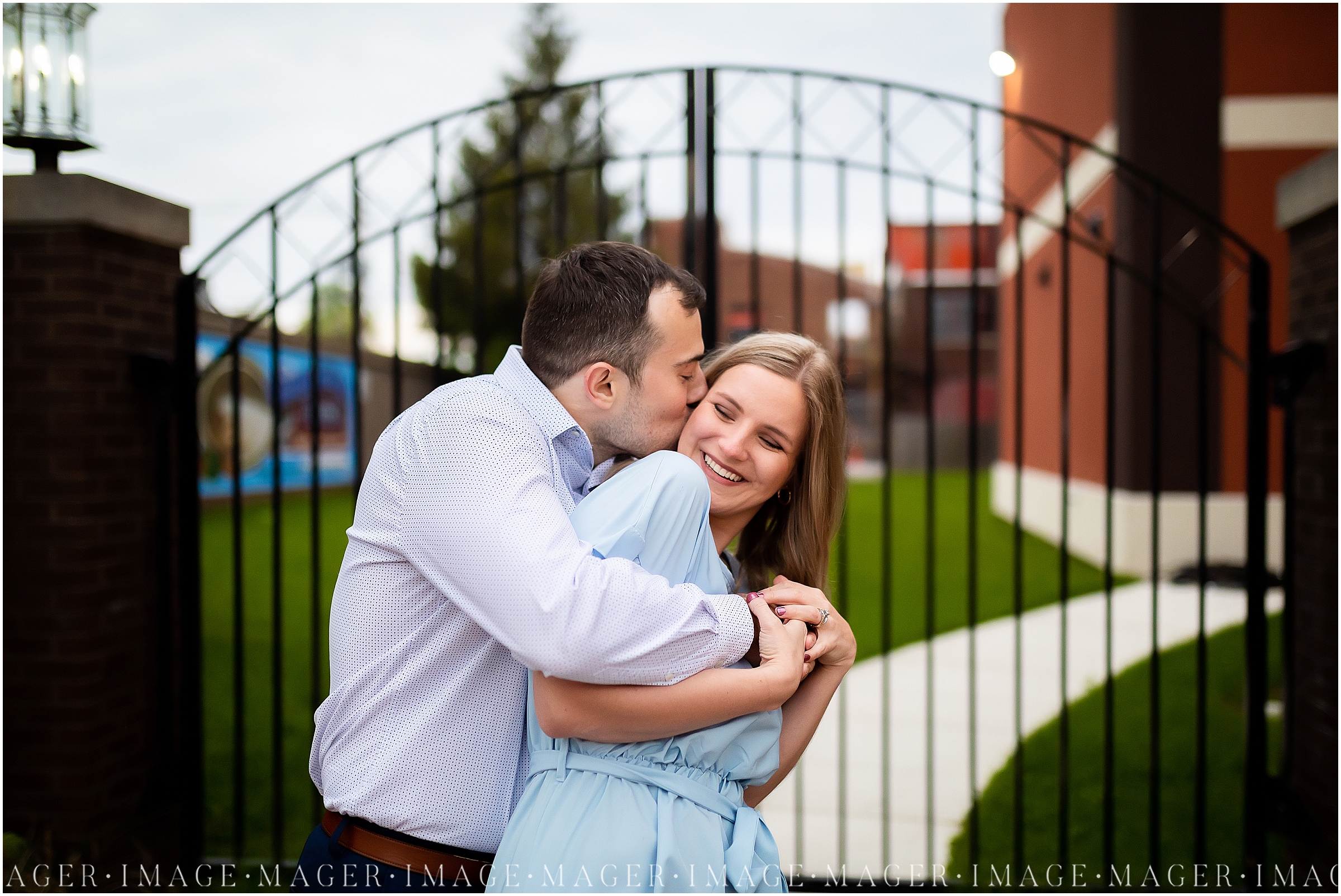 A man embraces his soon to be bride from behind while kissing her on the cheek at their downtown Danville, IL engagement session.

Photo taken by Mager Image Photography 