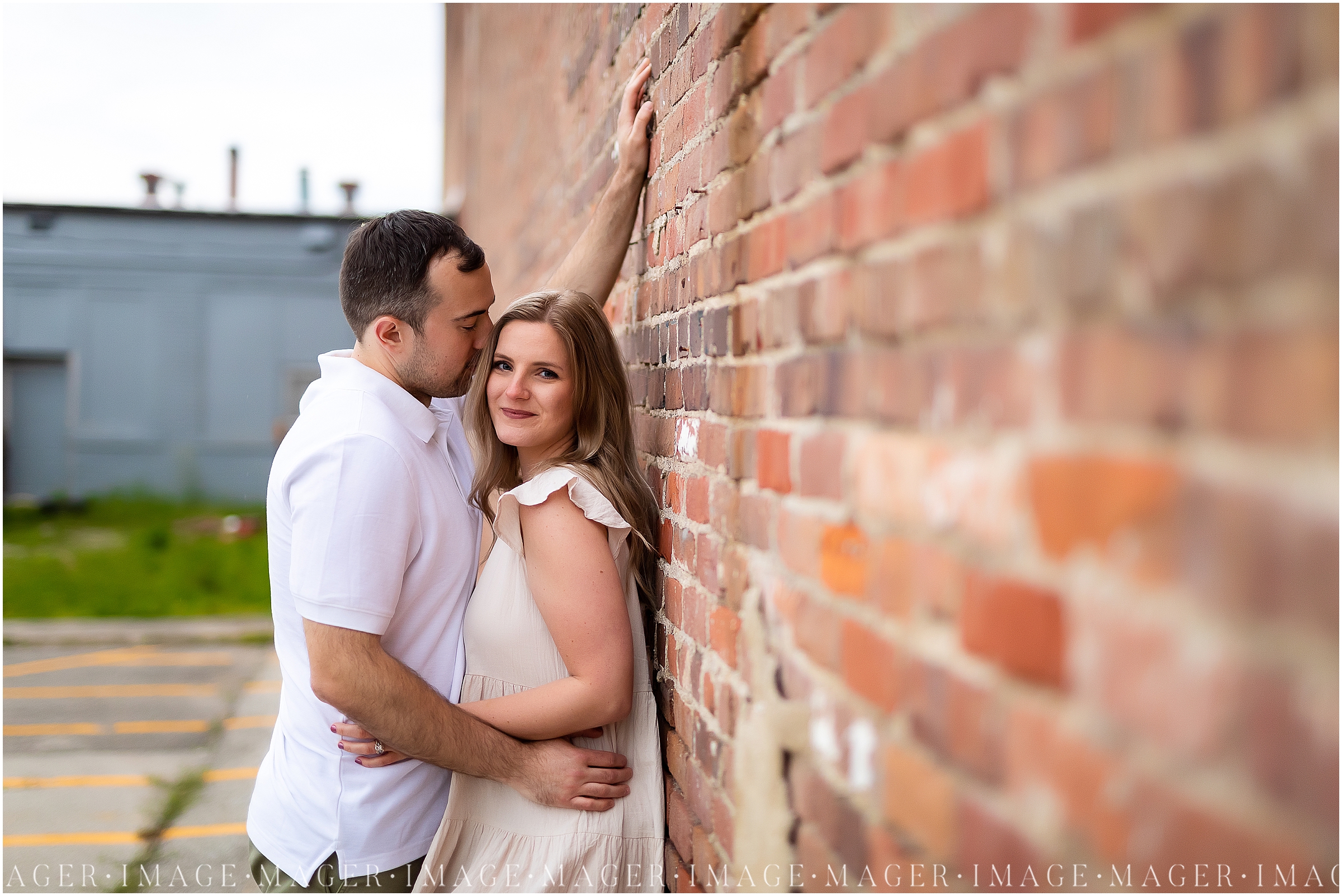 A couple embraces each other, the woman looking the camera while leaning against a wall and the man looking at her. Set by a brick wall in downtown Danville, IL.

Photo taken by Mager Image Photography 