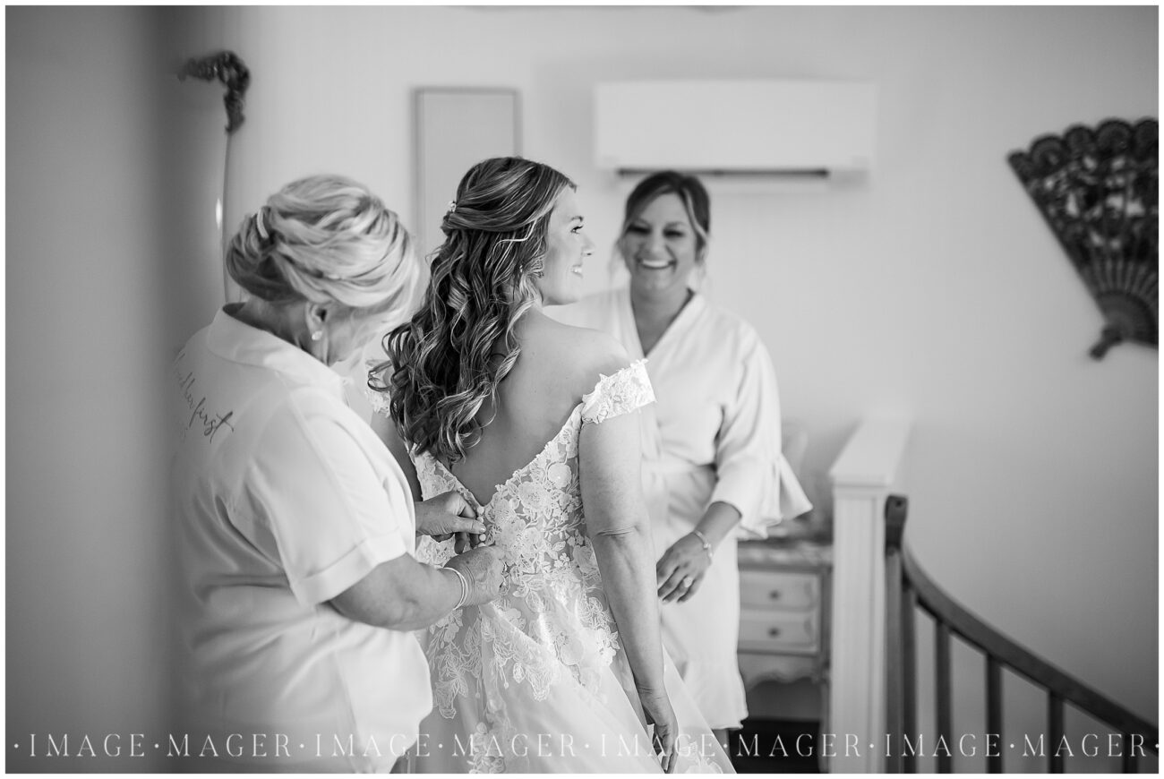 bride getting ready the morning of her wedding in white, ivory, and blush with mom and sisgter