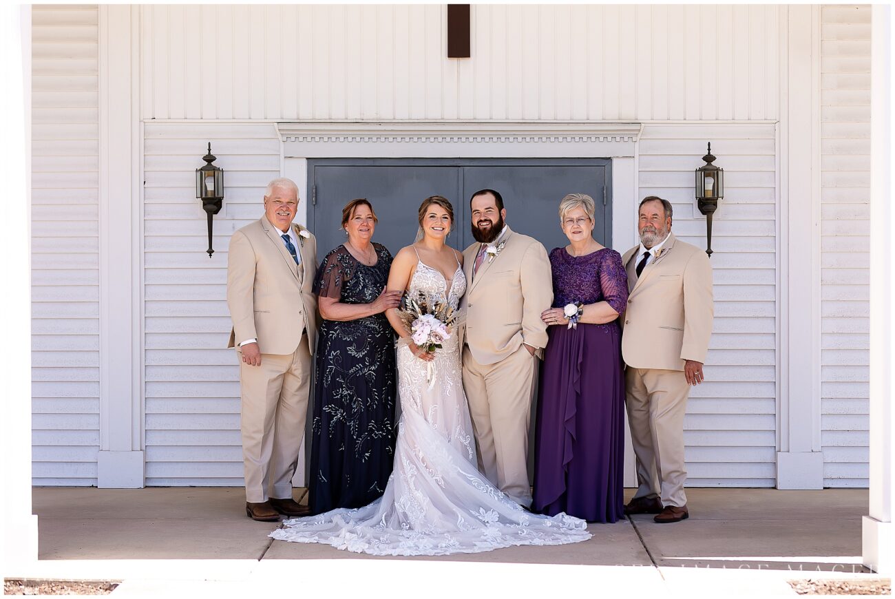 A small town wedding for Casey and Adam. The bride and groom pose with their parents for a portrait outside of the church's blue doors.

Saint John the Baptist Catholic Church, L'erable, IL. 

Photo taken by Mager Image Photography.