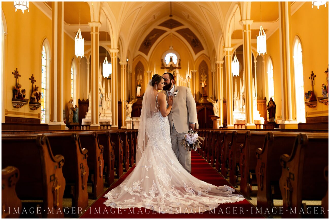 A small town wedding for Casey and Adam. A portrait of the bride and groom inside the detailed church building, showing off the back of the bride's dress.

Saint John the Baptist Catholic Church, L'erable, IL. 

Photo taken by Mager Image Photography.