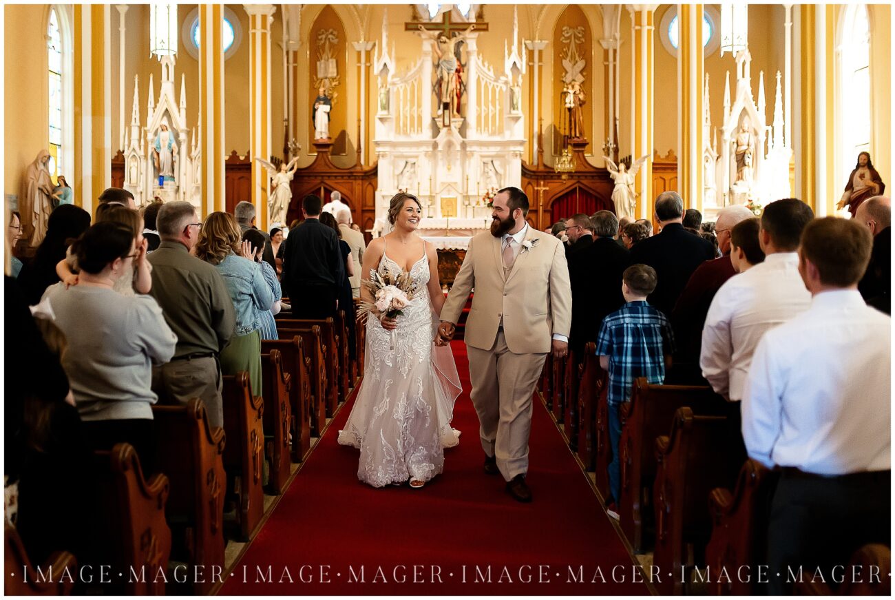 A small town wedding for Casey and Adam. A happy bride and groom walking down the aisle of the church after their wedding ceremony.

Saint John the Baptist Catholic Church, L'erable, IL. 

Photo taken by Mager Image Photography.